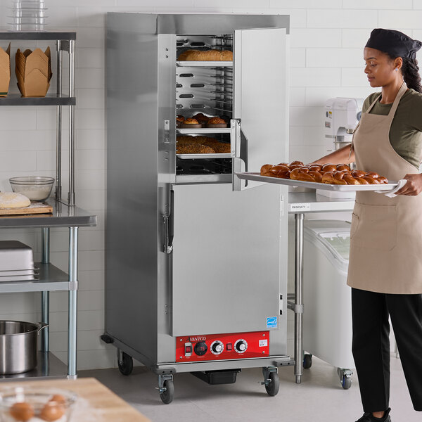 A full size insulated heated holding and proofing cabinet with solid stainless steel Dutch doors in a commercial kitchen setting.