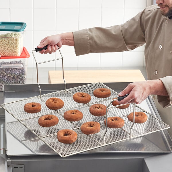 A man using an Avantco donut fryer screen to display donuts on a counter.