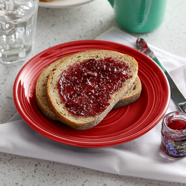 A Tuxton Concentrix cayenne china plate with bread and jam on it.