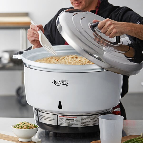 A man using an Avantco liquid propane gas rice cooker to cook rice in a large white pot.