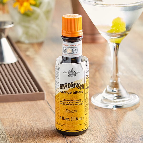 A bottle of Angostura Orange Bitters next to a martini glass filled with a cocktail.