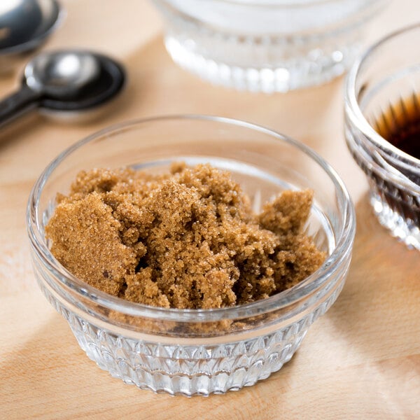 A bowl of dark brown sugar with a spoon in it.