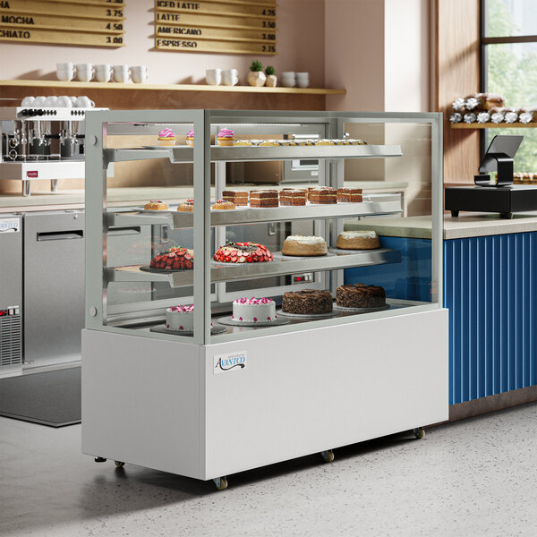 A white Avantco refrigerated bakery display case full of cakes with a glass front.