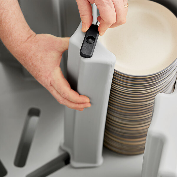 A person using a Noble Products dish dolly to stack plates on a table.