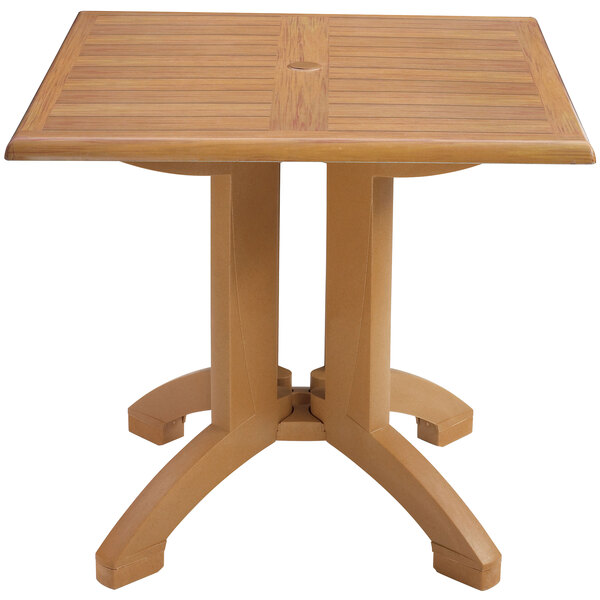 A Grosfillex Teak Decor square pedestal table with legs.
