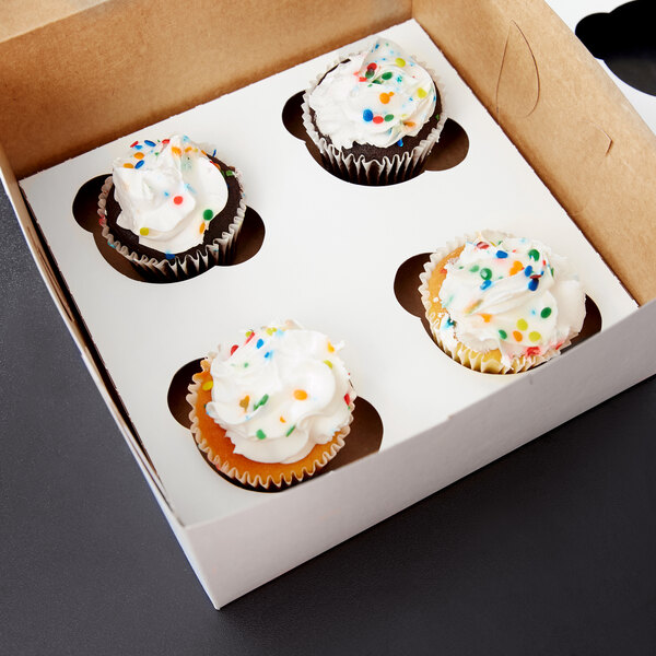 A Baker's Lane box of cupcakes with white frosting and sprinkles.