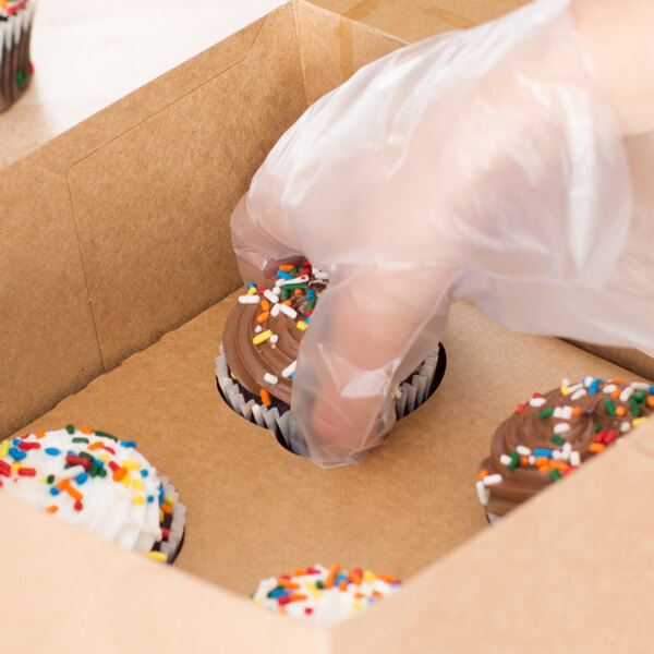 A person putting Baker's Lane Reversible Cupcake Inserts in a box with cupcakes.