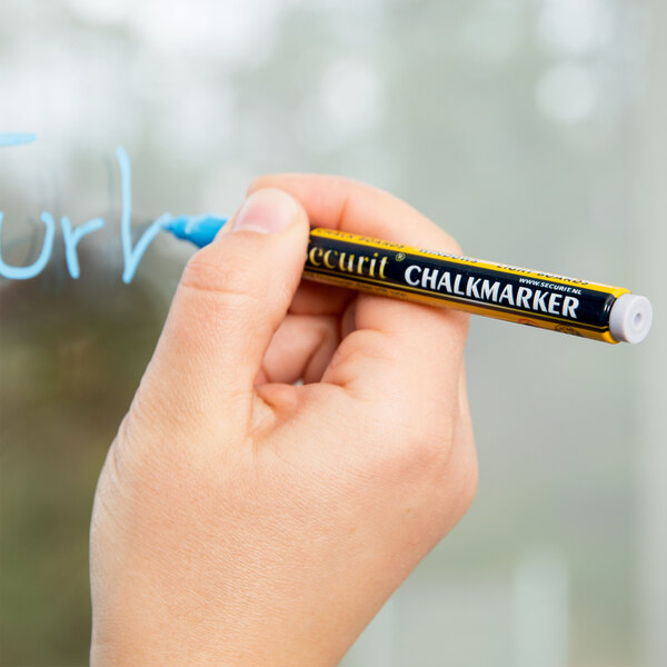 A person holding a yellow, black, and blue Securit mini tip chalk marker writing on a glass.