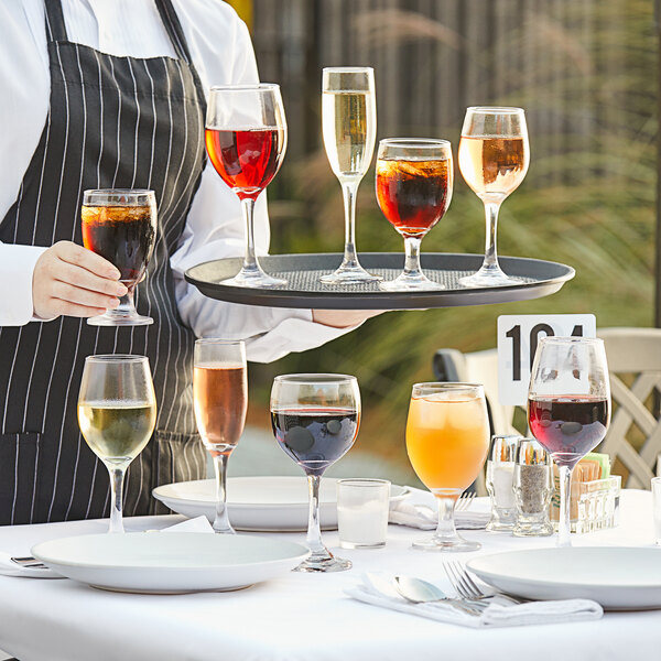 A person holding a tray of Acopa Balloon Wine Glasses full of red wine.