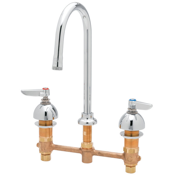 A white deck-mount faucet with two brass lever handles.