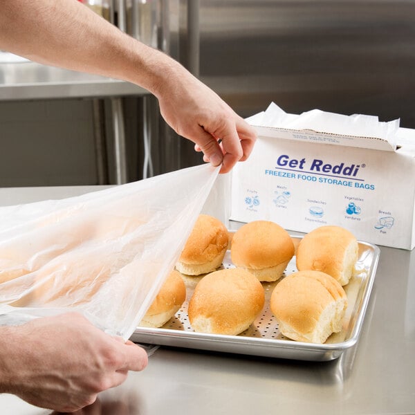 A person putting an Inteplast Group plastic bag on a tray of buns.