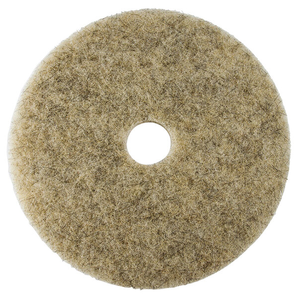 A beige circular Scrubble floor pad with a hole in the middle.