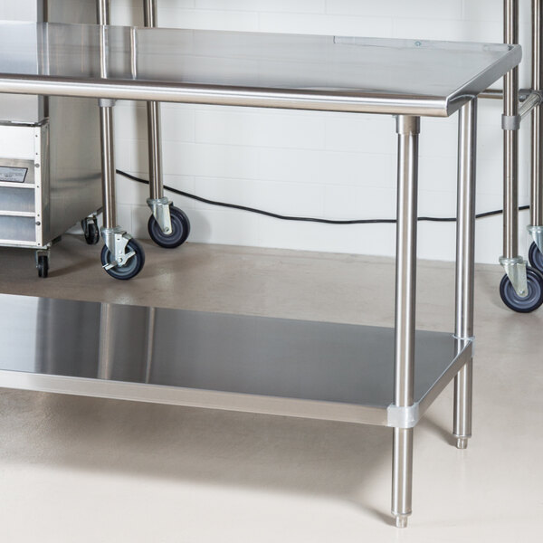 A stainless steel Advance Tabco work table with undershelf and wheels.