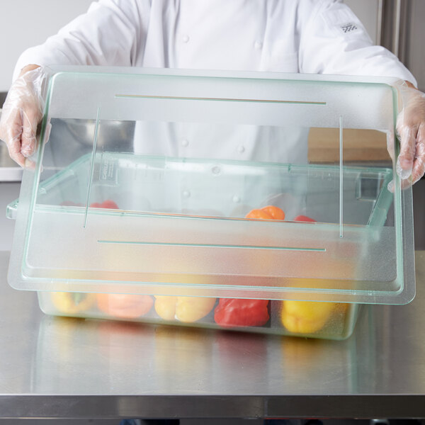 A person holding a Carlisle food storage box lid filled with peppers.