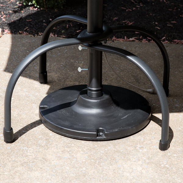 A black metal Grosfillex umbrella base on a table outdoors.