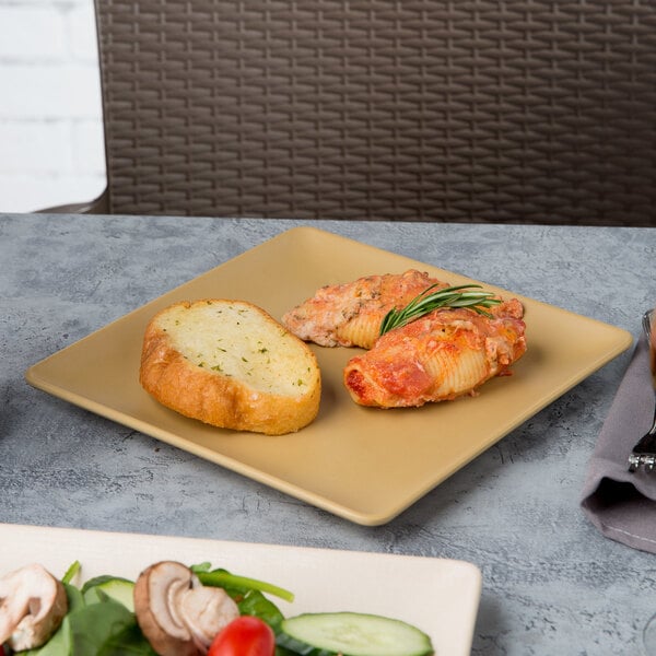 An Elite Global Solutions rattan-colored square melamine plate with pasta and bread on a table.