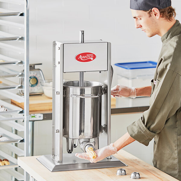 A man using an Avantco stainless steel churro stuffer.