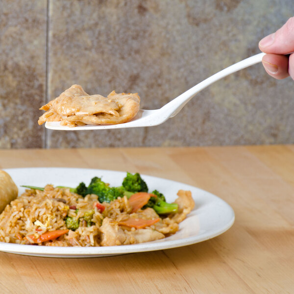A hand using a Thunder Group Blue Bamboo melamine spatula to serve food on a plate.