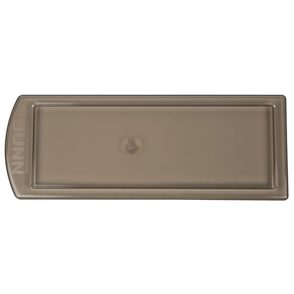 A rectangular brown plastic lid with a hole in it.
