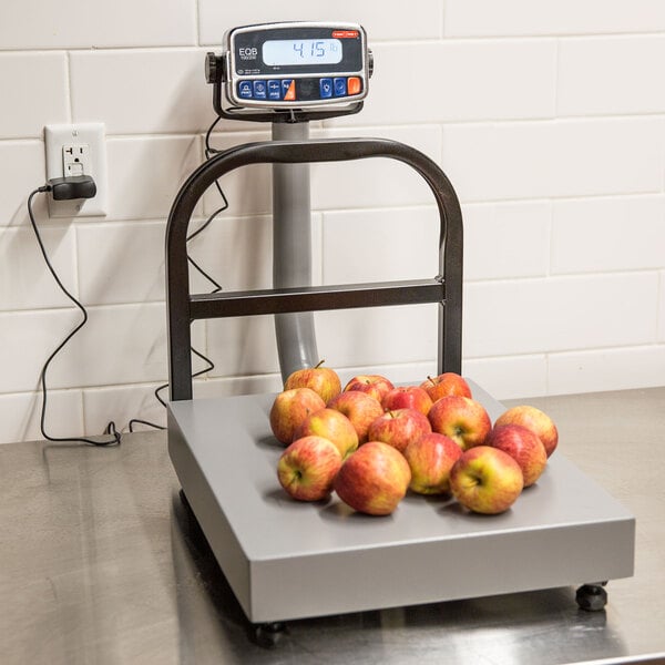A Tor Rey digital receiving scale on a counter with a group of apples on it.
