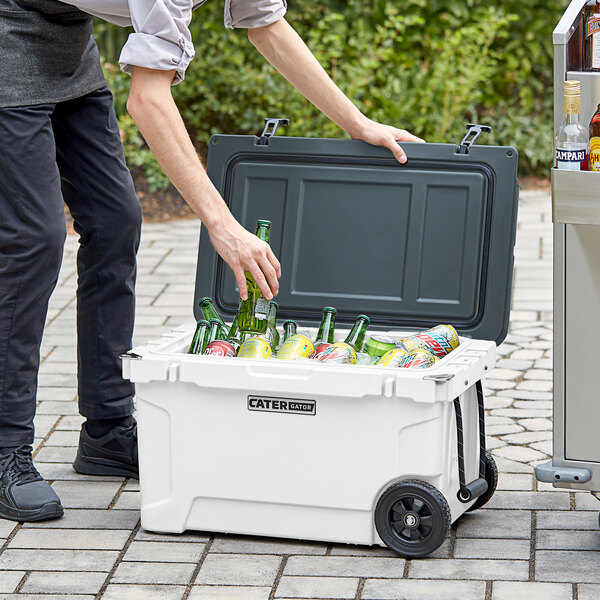 A person holding a CaterGator outdoor cooler full of bottles.