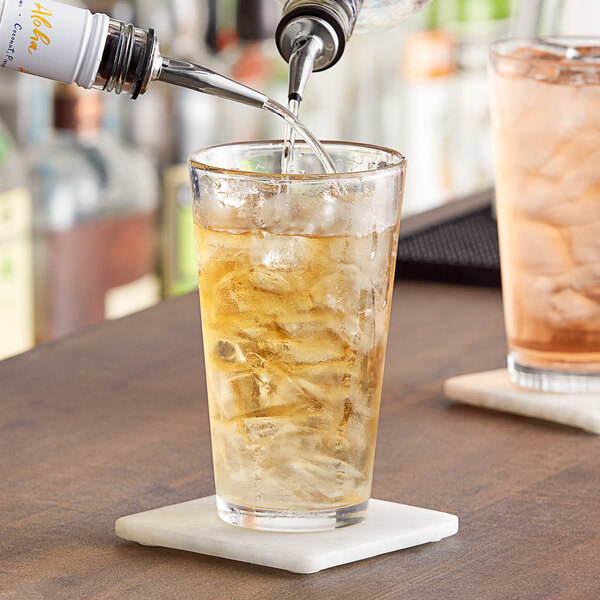 A bartender pouring a drink into an Acopa mixing glass.