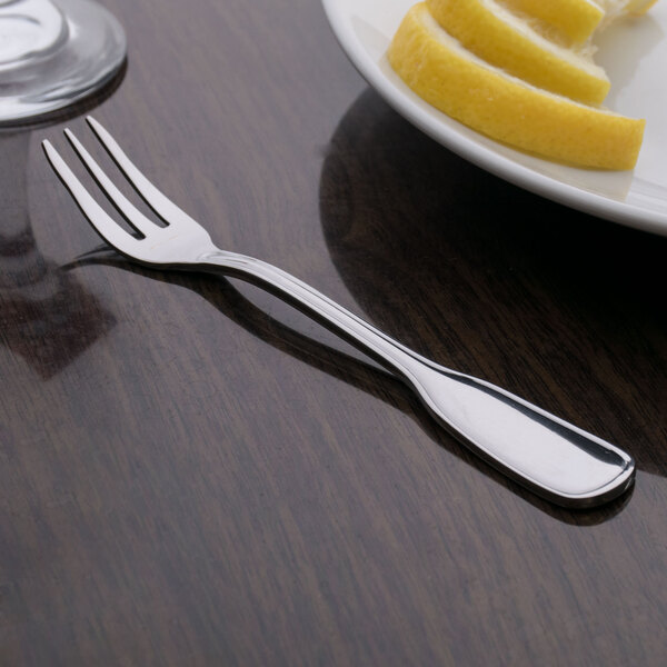 A Oneida Stanford stainless steel cocktail fork on a table with a lemon.