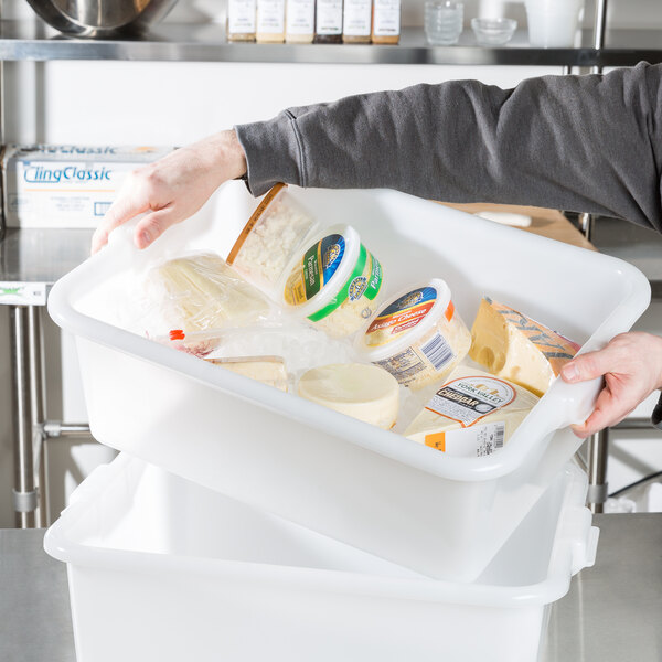 A person holding a white Vollrath Traex plastic container full of cheese.