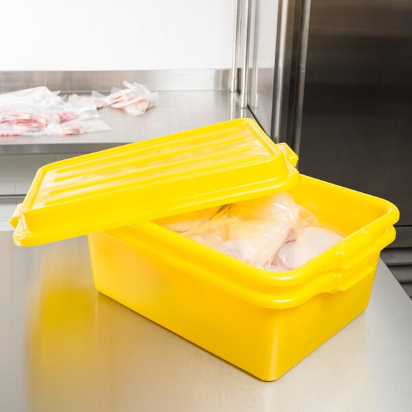 A yellow Vollrath Traex food storage bin with food inside and the lid open.