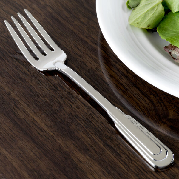 A Oneida Cityscape stainless steel salad fork on a plate with a salad.