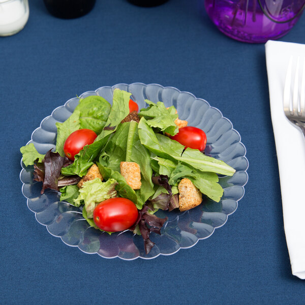 A salad with tomatoes and croutons on a Fineline Flairware clear plastic plate.