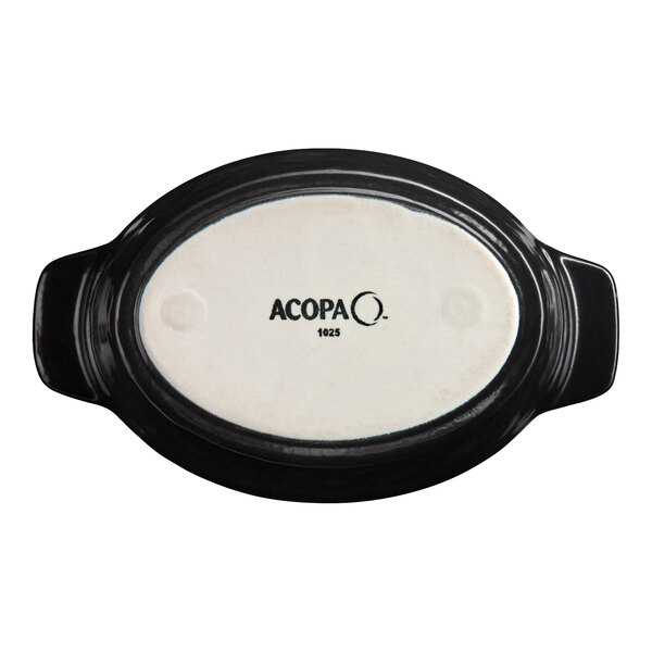 A small black and white oval porcelain rarebit dish with handles, shown from the bottom with the Acopa brand name.