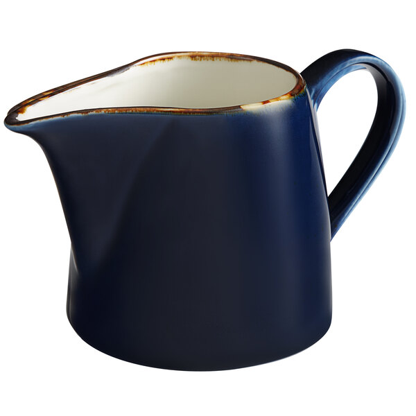 An Acopa Keystone blue and white porcelain creamer with a gold rim.