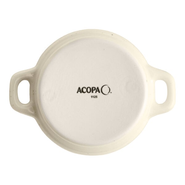 An 8 oz. vanilla bean porcelain mini casserole dish with handles, shown from the bottom with the Acopa brand mark.