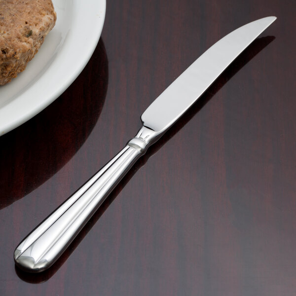 A Oneida Unity stainless steel steak knife on a plate.