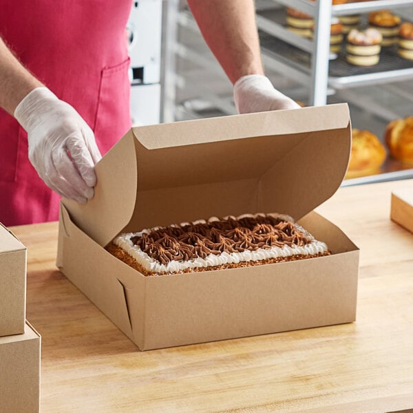 A person in gloves placing a cake in a Baker's Lane cake box.