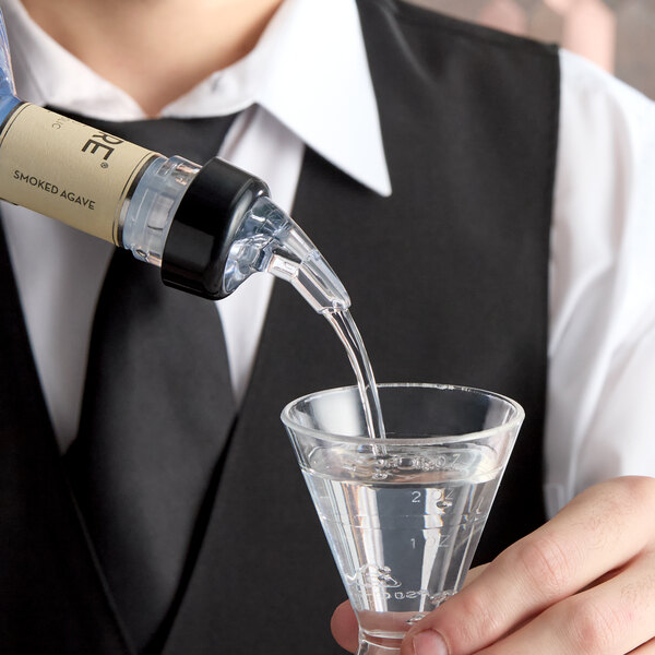 A 2 oz. 3-ball measured liquor pourer with a collar being used to pour liquid into a measuring glass.