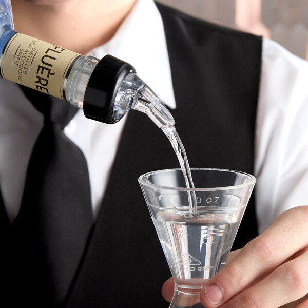 A clear measured liquor pourer with a collar dispensing liquid into a jigger.