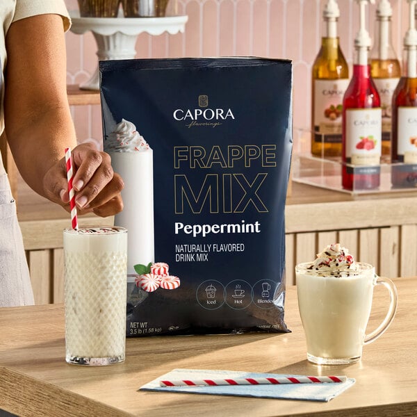 A 3.5 lb. bag of Capora Peppermint Frappe Mix displayed on a counter with prepared peppermint drinks.