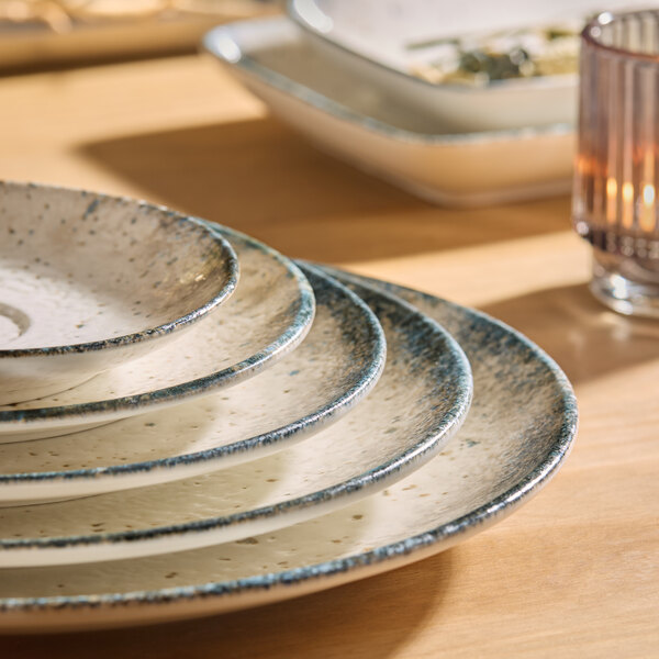 A stack of round gray porcelain coupe plates with a speckled design.
