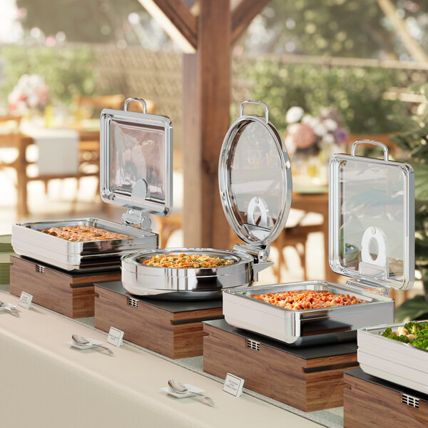 An outdoor buffet table with Acopa Manchester chafing dishes on it.