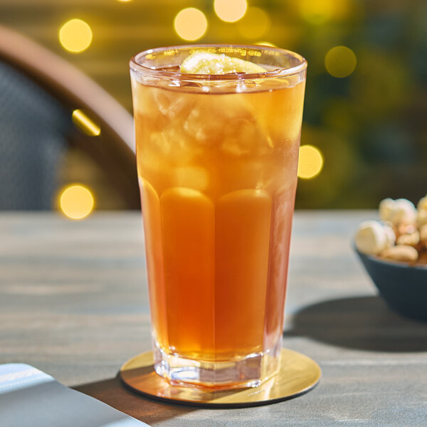 An Acopa Memphis cooler glass of orange liquid with ice on a table.