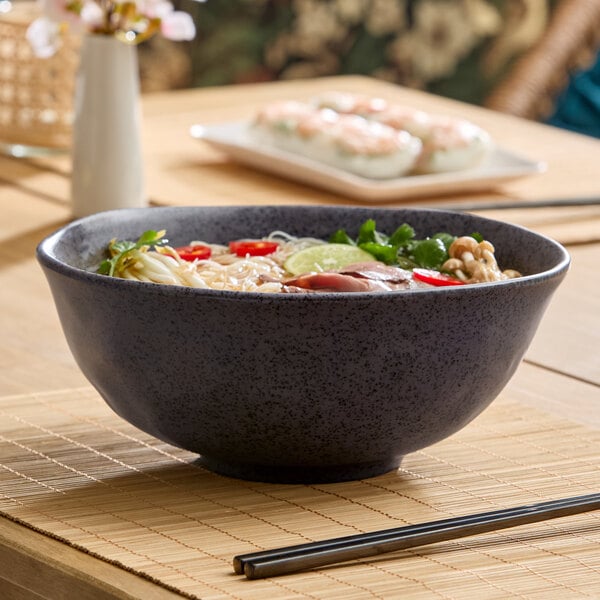 A large dark gray round melamine bowl filled with food, placed on a table.