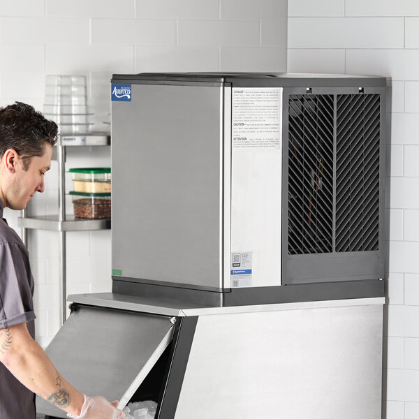 A commercial air-cooled modular full cube ice machine on top of an ice storage bin.