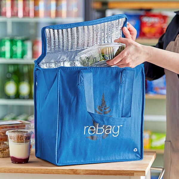 A person putting a plastic container of food into a blue ReBag.