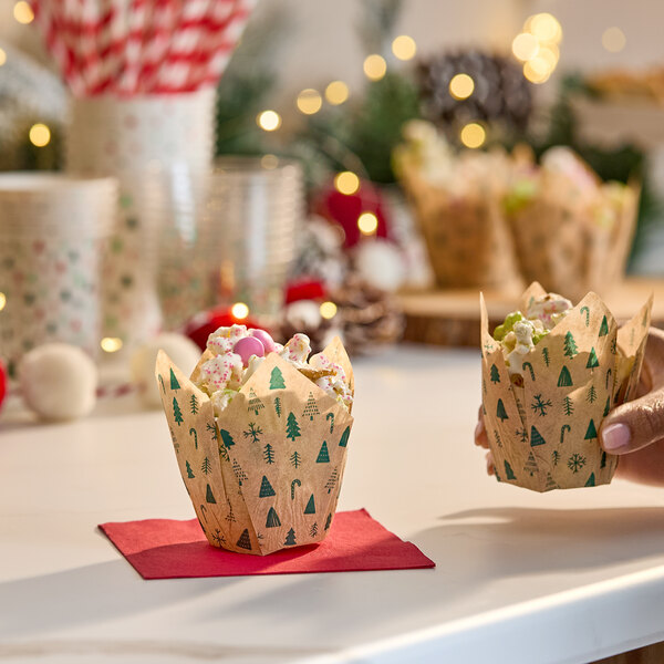 A modern Christmas green print tulip baking cup filled with treats, displayed on a festive table.