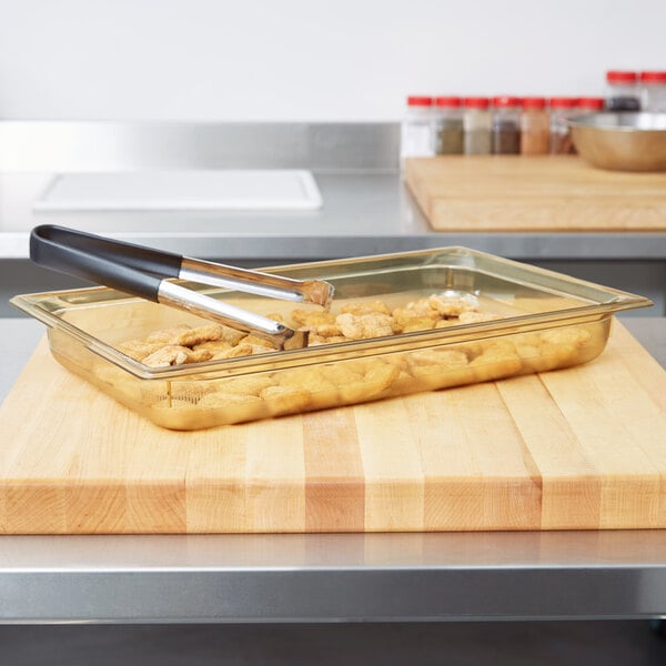 A Vollrath amber plastic food pan with food on a cutting board.
