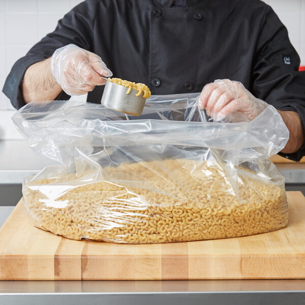 A man in a chef's uniform holding an LK Packaging plastic food bag of pasta.