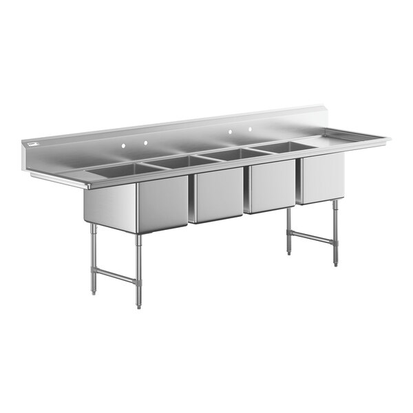 A large stainless steel commercial sink with four deep compartments and two side drainboards, supported by metal legs.