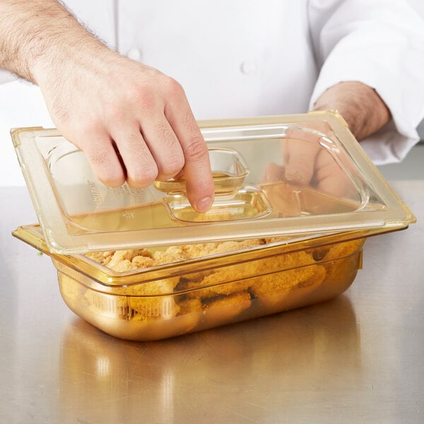 A person putting a Vollrath amber high heat lid on a food container.